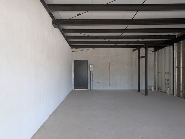 Interior del local desde el frente, paredes lisas y piso de concreto.